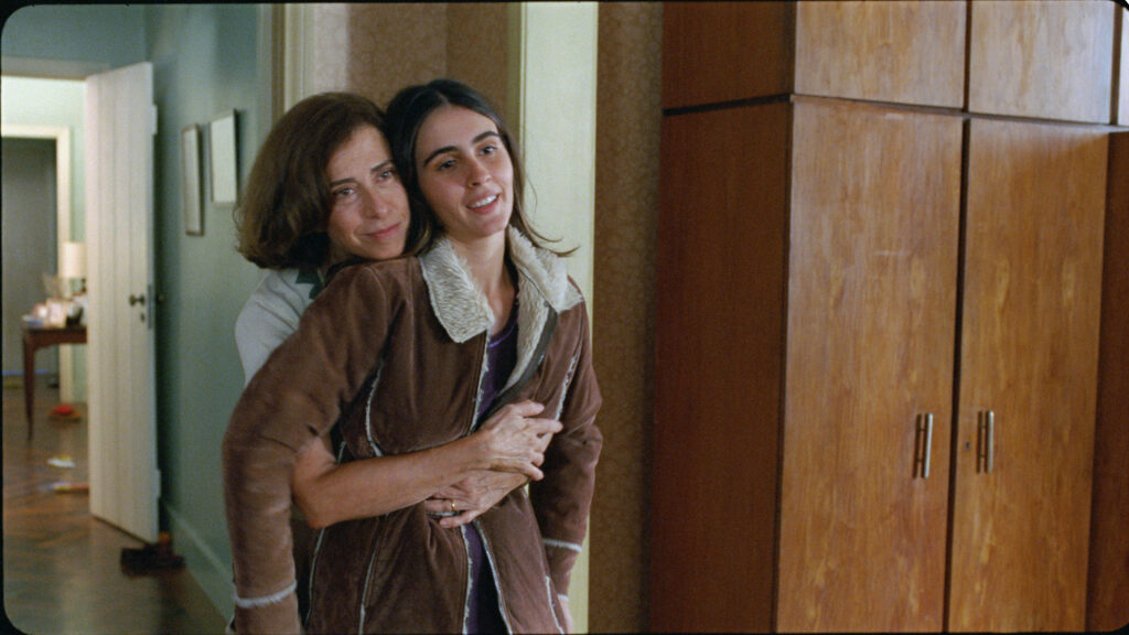Vera Paiva (Valentina Herszage) pede para a mãe, Eunice Paiva (Fernanda Torres) um casaco para sua viagem a Londres.